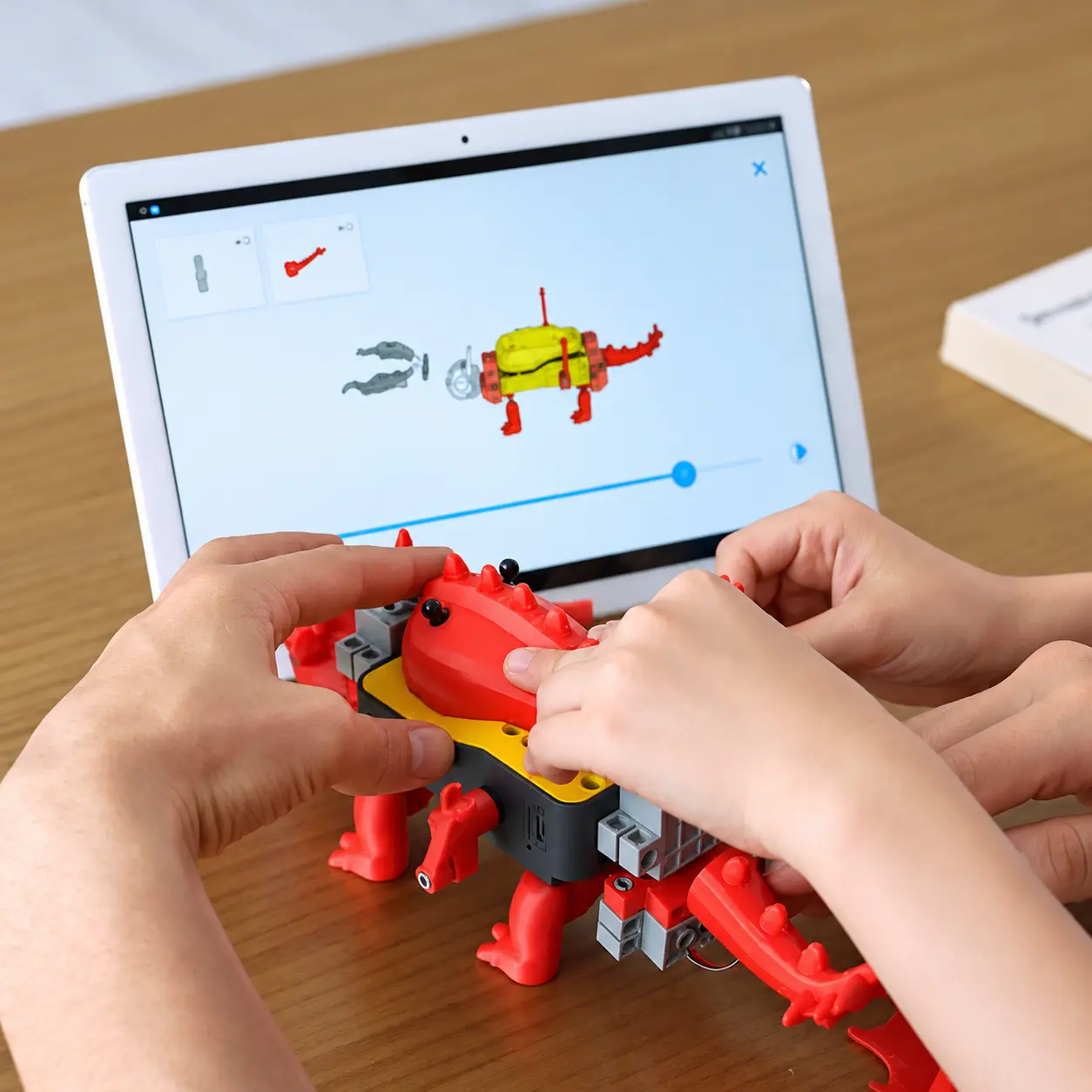 Dłonie przy wydrukowanym robocie sterowanym aplikacją na tablecie