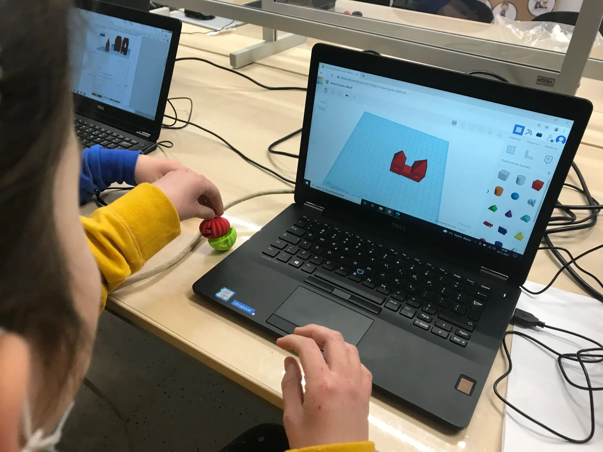Dziecko przy laptopie z otwartym projektem 3D, obok gotowy wydruk