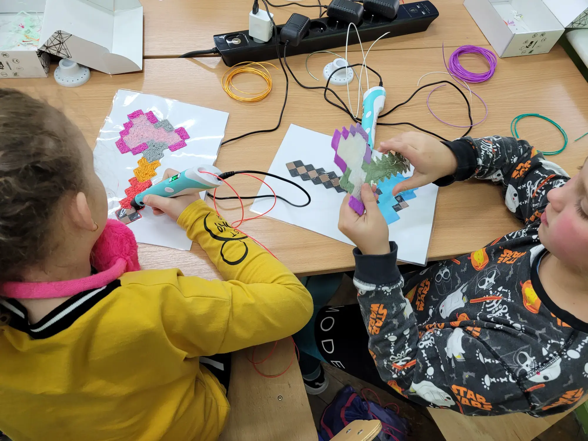 Dzieci tworzą kolorowe prace długopisami 3D na szablonach