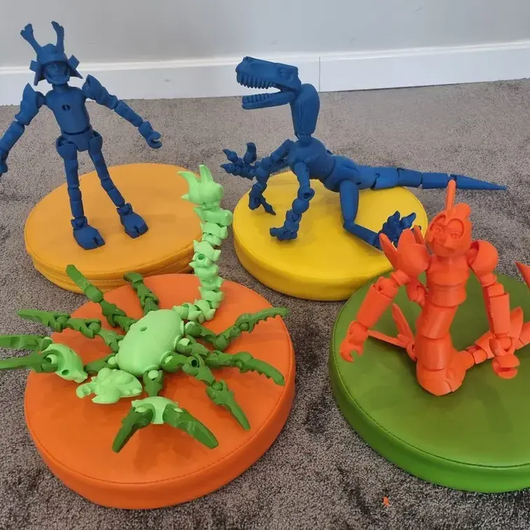Wydrukowane w 3D figurki dinozaurów i robotów na kolorowych podstawkach